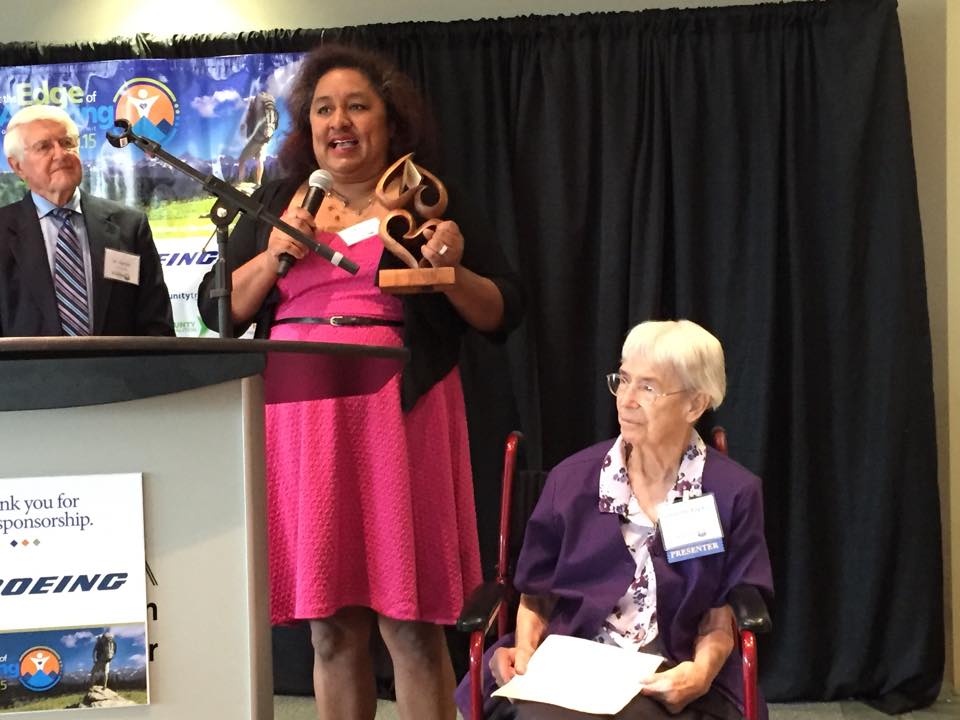 Sanda Solano-Huber, Program Coordinator for Familias Unidas, accepts the “ChangeMaker” Award presented by Sister Georgette Bayless (seated).
