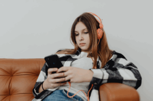 teenage girl wearing headphones and looking at phone