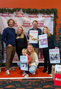 family holding signs of the items they donated at the Giving Machine
