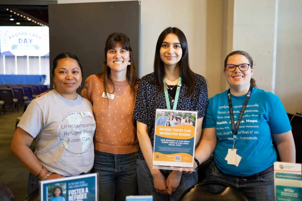 4 people are standing together at an information table.