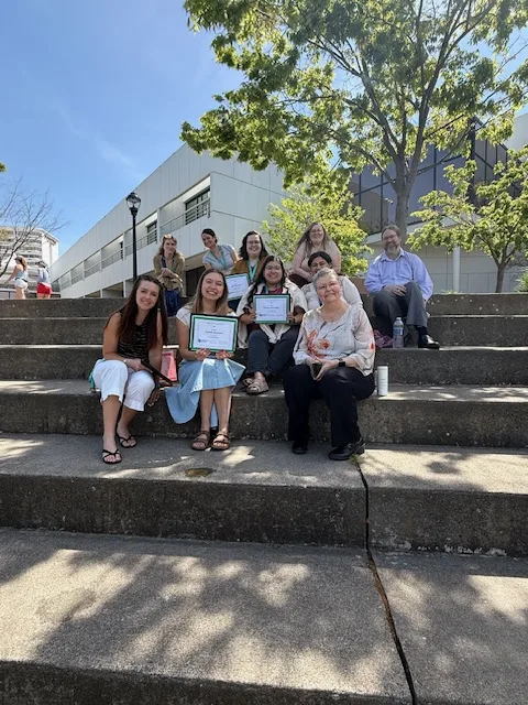 A group of ten people are grouped together on a set of outdoor steps, smiling.